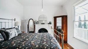 Un dormitorio con una cama, un espejo, una chimenea y una ventana.
