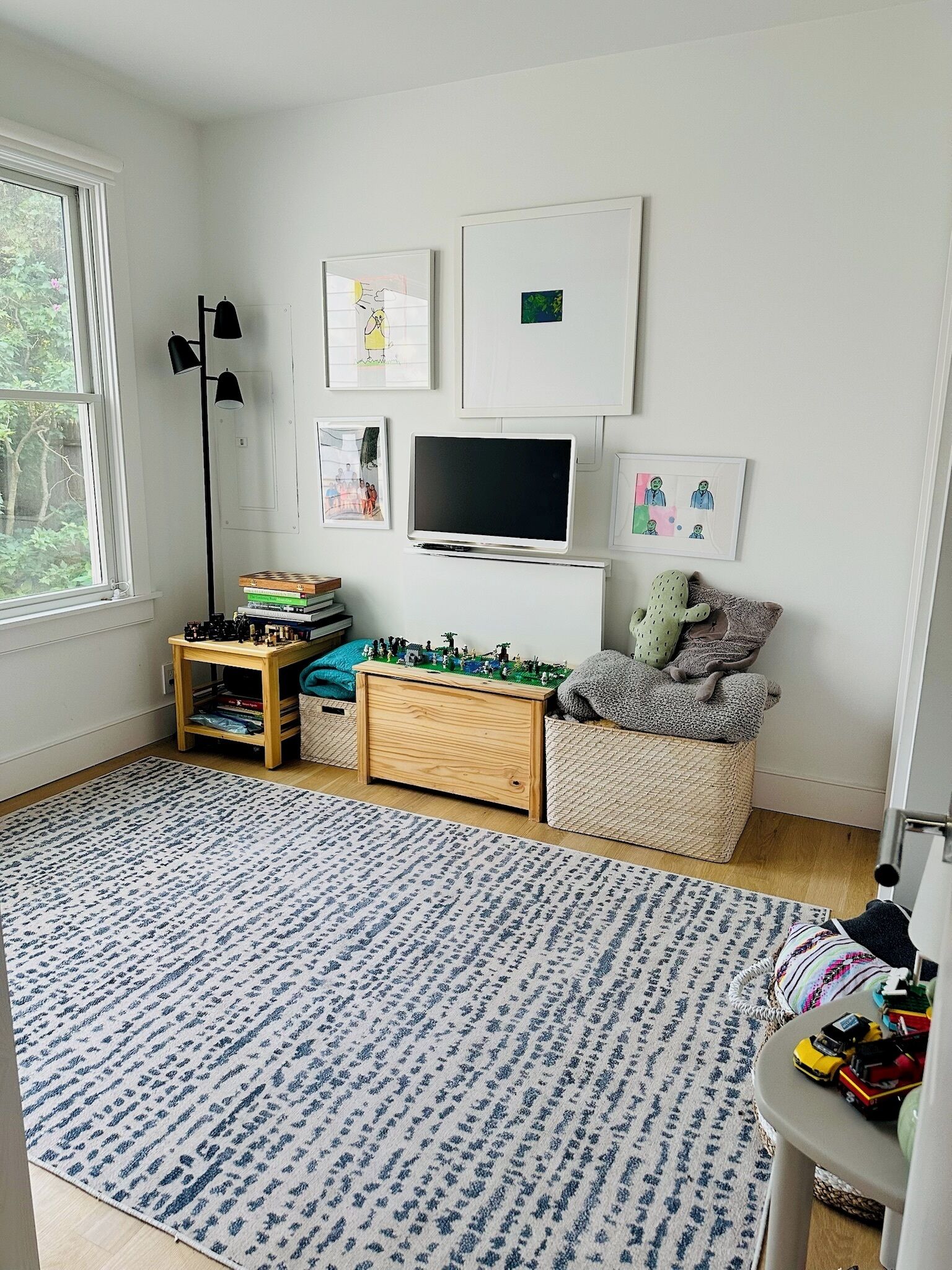 A child's playroom with a television, books, toys, and artwork on the wall.