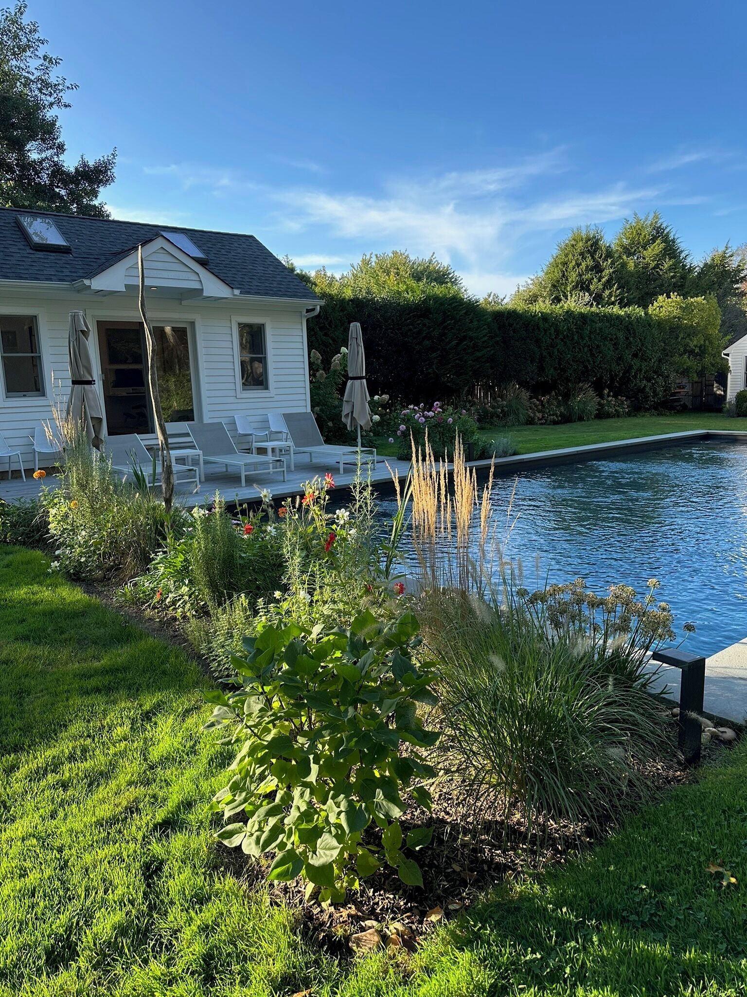 Ein Wohnhaus mit Schwimmbad, einer Terrasse und Gartenmöbeln sowie einem gepflegten Garten.
