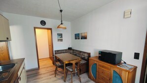 Ett kompakt kök med träskåp, ett matbord och en mikrovågsugn placerad på ett av träskåpen.