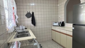 Eine Küche mit einem Edelstahl-Kühlschrank, einem Spülbecken und einer Arbeitsplatte mit Wasserkocher und Toaster.