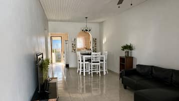 A spacious living area with a dining table and chairs, a sofa, and a ceiling fan.