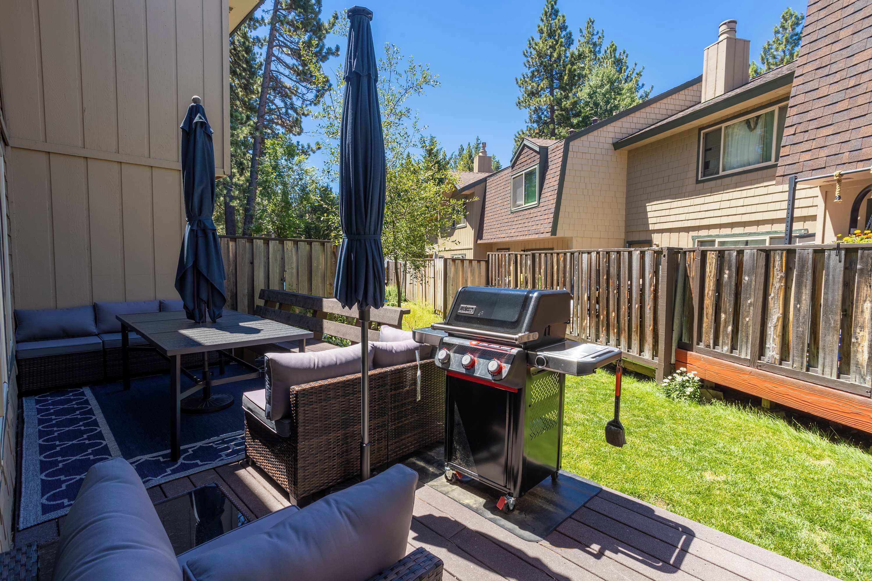 A backyard with a grill, outdoor furniture, and a wooden fence.
