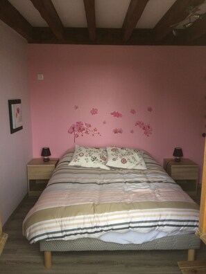 A bedroom with a bed, two bedside tables, and a pink wall with floral decorations. - COMFORTABLE VACATION RENTAL IN APPRIEU, BETWEEN THE VERCORS AND THE CHARTREUSE (Apprieu)