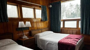 A room with two beds, wooden walls, a window, and a nightstand with a lamp. - Cozy 1BR hotel room, Hamilton - #342 Rode-A-Syde (Hamilton)