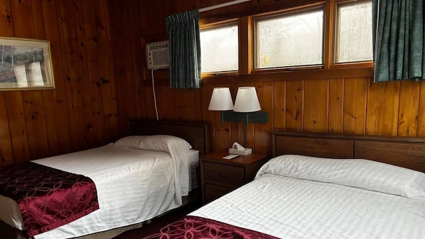 A room with two beds, wooden walls, a window with curtains, and a nightstand with lamps. - Cozy 1BR hotel room, Hamilton - #342 Rode-A-Syde (Hamilton)