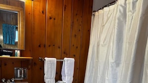 A bathroom with a wooden interior, a white sink, a toilet, and a shower curtain. - Cozy 1BR hotel room, Hamilton - #342 Rode-A-Syde (Hamilton)