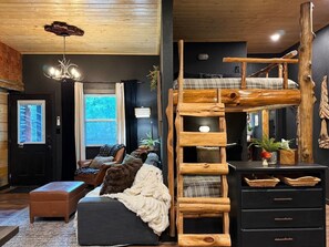A cozy room with a bunk bed, a wooden ladder, a desk with drawers, and a large window. - Fern & Feather No 1 at Cedar Creek Crossing (Mena)