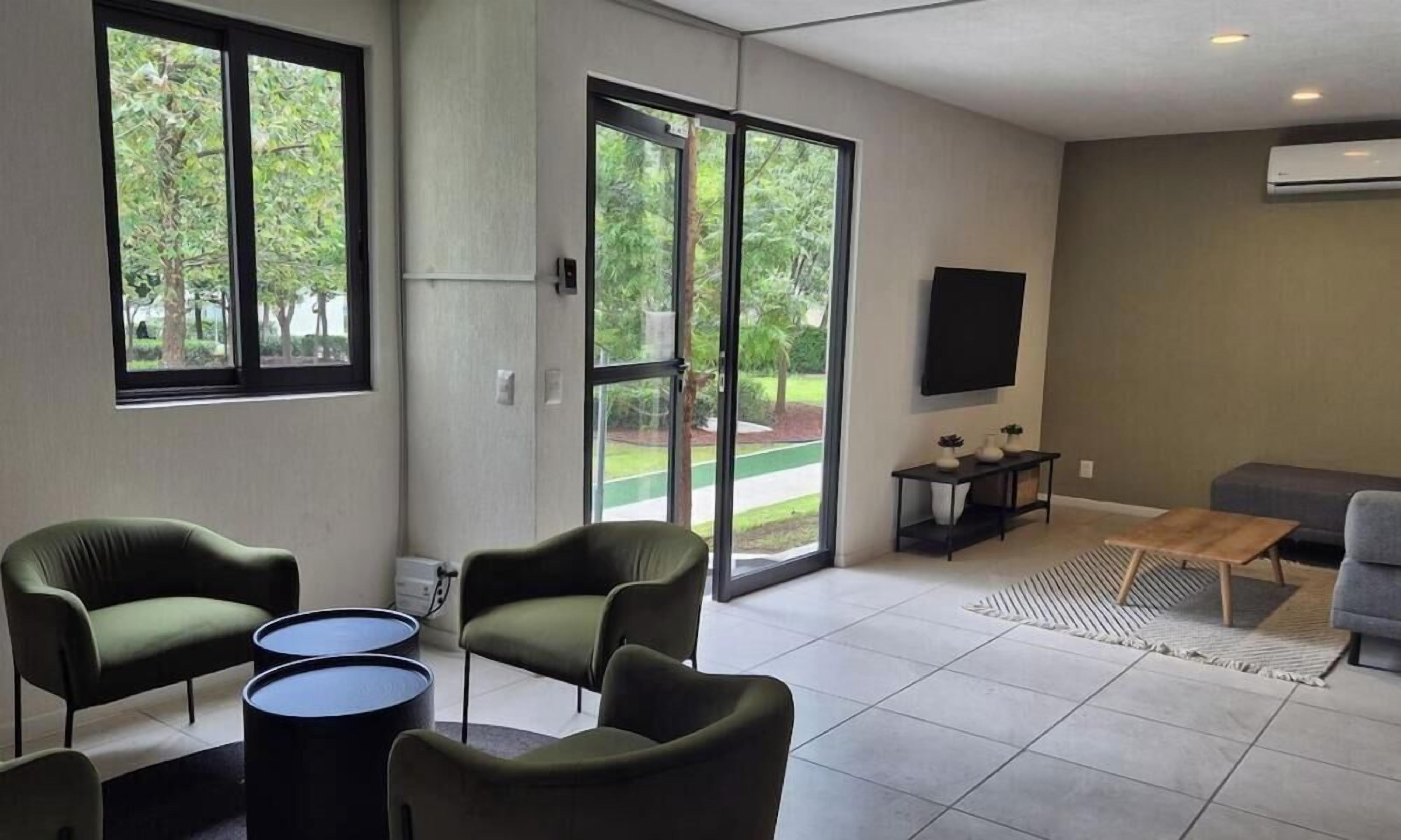 Un salon moderne comprenant un canapé, deux fauteuils, une table basse et un téléviseur à écran plat fixé au mur.