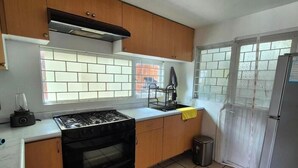 Eine Küche mit Holzausstattung, einem Gasherd, einer Spüle und einem Kühlschrank.