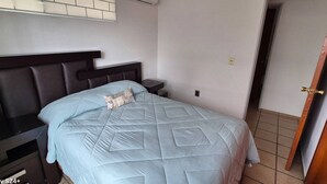 Ein Schlafzimmer mit Bett, Nachttisch, Wand-Klimaanlage und einer Tür.