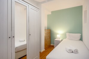 A bedroom with a bed, a nightstand, a dresser, and a closet. - Santana Cosy by Homing (Lisbon)