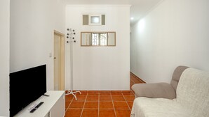 Un pasillo con una televisión, una silla y una puerta.
