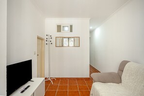 A hallway with a television, a chair, and a door. - Santana Cosy by Homing (Lisbon)