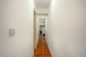 A narrow hallway with white walls and a tiled floor leading to a kitchen area. - Santana Cosy by Homing (Lisbon)