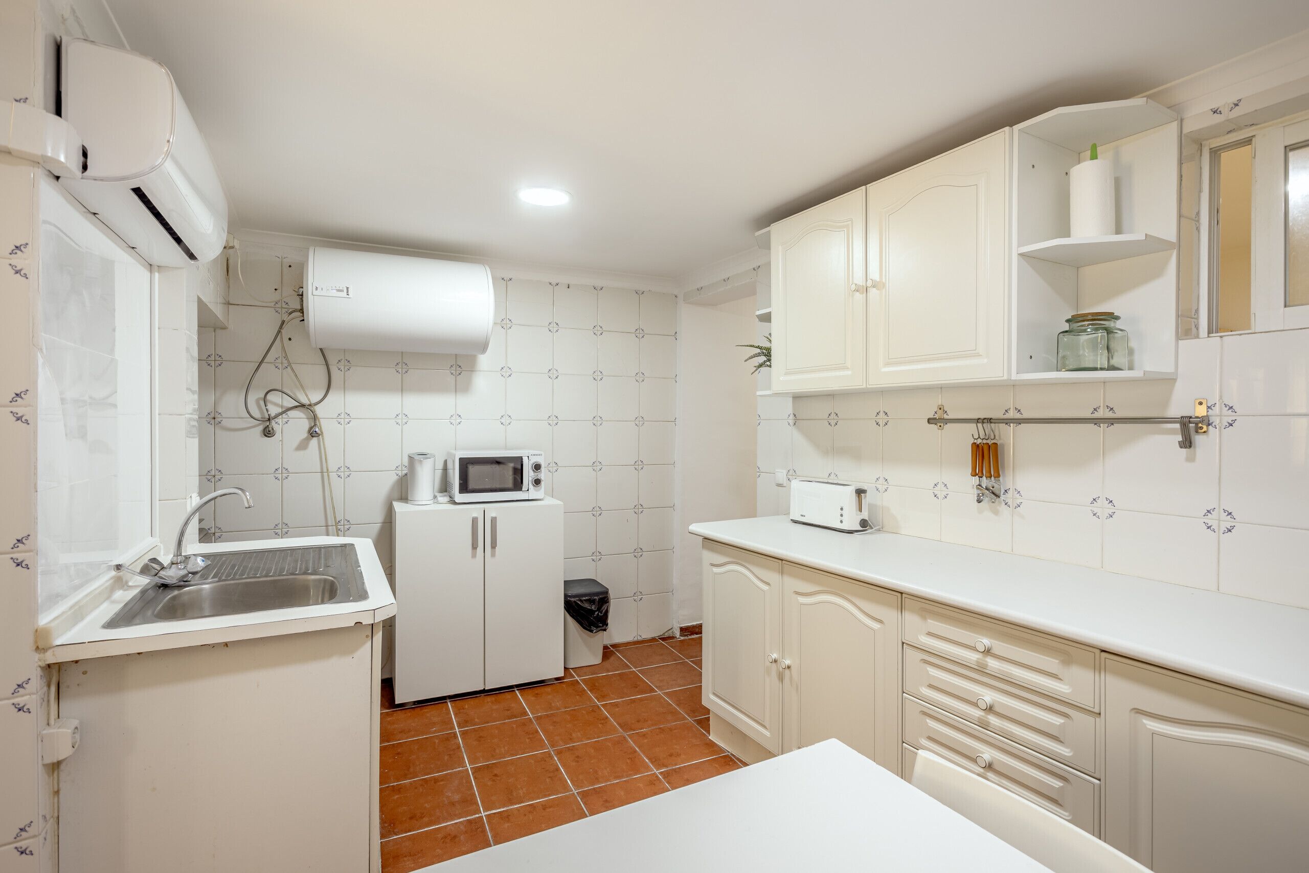 A compact kitchen with white cabinets, a microwave, a toaster, and a sink.