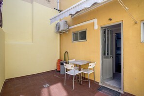 A small outdoor patio with a table and chairs, an air conditioning unit, and a door leading to an interior space. - Santana Cosy by Homing (Lisbon)