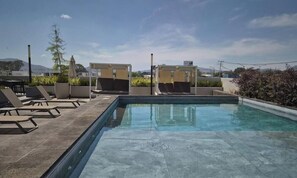 A rooftop pool area with lounge chairs and a clear view of the cityscape. - Depa Punto Sur 2 rec 2 baños alberca piso 9 (Santa Anita)