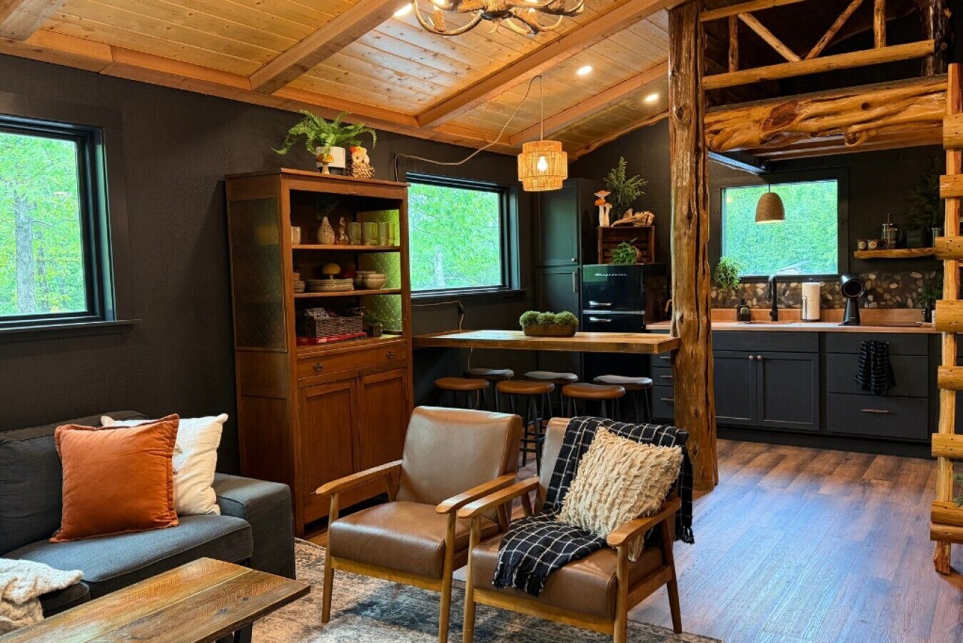 Un intérieur chaleureux avec un plafond en bois, un canapé, un coin repas et une cuisine.