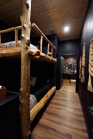 A bunk bed with a rustic design, a dark-colored sofa, and a wooden floor. - Cedar Creek Crossing (all 4 units) (Mena)