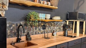 Cocina con salpicadero de piedra, encimera de madera y armarios negros.