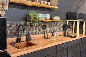 A kitchen with a stone backsplash, wooden countertop, and black cabinets. - Cedar Creek Crossing (all 4 units) (Mena)