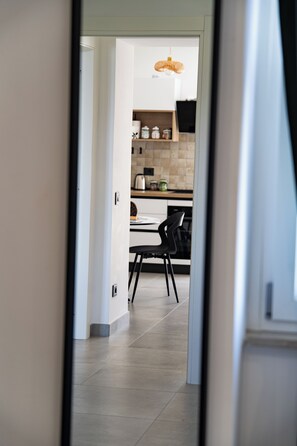 Eine moderne Küche mit Essbereich, ausgestattet mit einer Kücheninsel, Stühlen und einer Pendelleuchte.