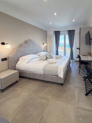 Ein modernes Hotelzimmer mit einem großen Bett, einem Schreibtisch und Meerblick.