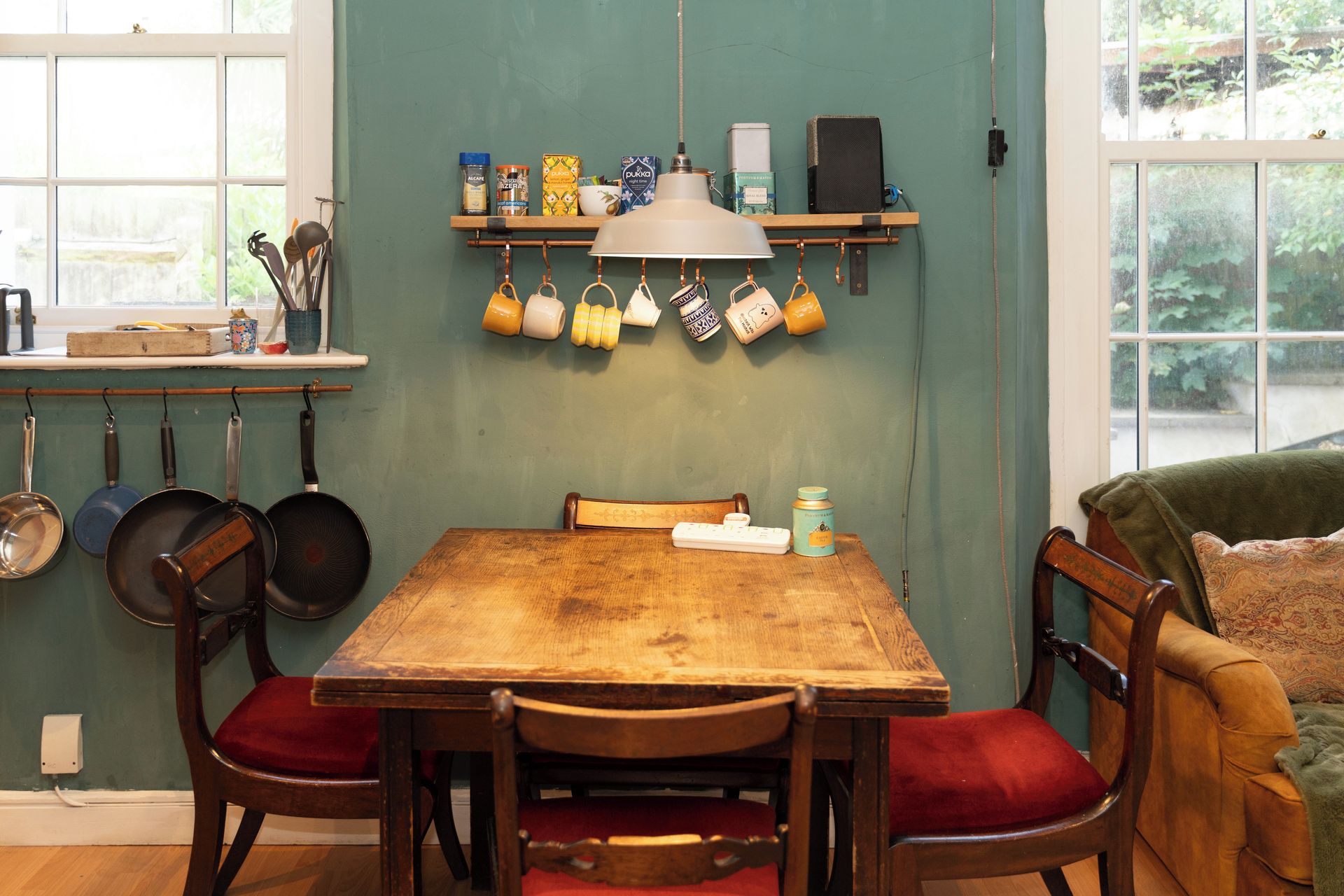 Un espace repas comprenant une table en bois, des chaises et un luminaire suspendu.