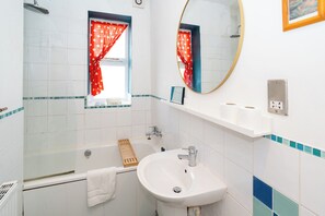A bathroom with a bathtub, sink, and a mirror. - 1BDR 1BA Flat on Vibrant Gloucester Road (Bristol City)