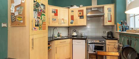 Een keuken met houten kastjes, een fornuis, een vaatwasser en een spoelbak.
