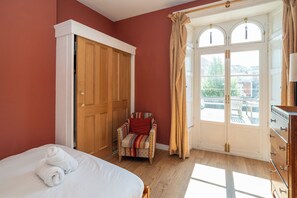 Une chambre à coucher avec un lit, une chaise, une armoire et une fenêtre avec des rideaux.
