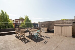 A rooftop patio with a table and chairs, a lantern, and a storage shed. - 1BDR 1BA Flat on Vibrant Gloucester Road (Bristol City)