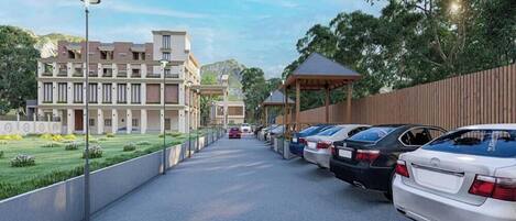 A parking area with cars, a building with multiple floors, and a covered walkway.