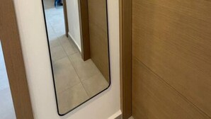 A room with a large mirror, wooden wardrobe, and a bed with blue bedding. - Departamento Nhaos Minerva (Guadalajara)
