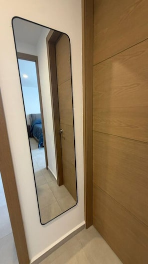 A room with a large mirror, wooden wardrobe, and a bed with blue bedding. - Departamento Nhaos Minerva (Guadalajara)