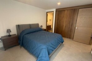 Ein Schlafzimmer mit Bett, Nachttisch, Kleiderschrank und angrenzendem Badezimmer.