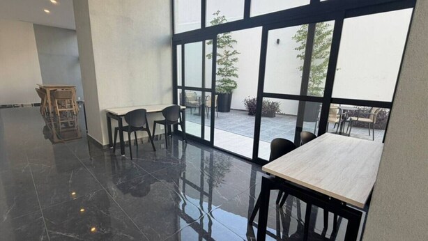 A modern interior with a polished floor, large windows, and a seating area with tables and chairs. - Departamento Nhaos Minerva (Guadalajara)