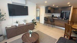 A modern living room with a flat-screen TV, a round wooden coffee table, and a seating area with a sofa and chairs. - Departamento Nhaos Minerva (Guadalajara)