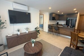 A modern living room with a flat-screen TV, a round wooden coffee table, and a seating area with a sofa and chairs. - Departamento Nhaos Minerva (Guadalajara)