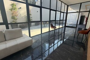 A modern interior with a glass partition, a sofa, and a dining area. - Departamento Nhaos Minerva (Guadalajara)
