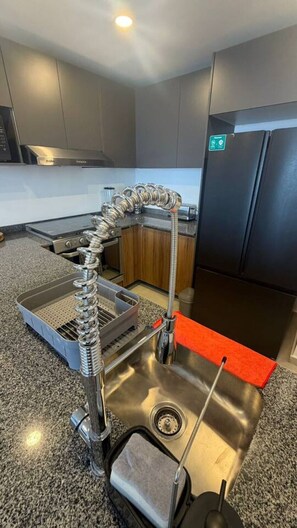 Eine Küche mit einer Spüle aus Edelstahl, einem Einbauofen und einem Kühlschrank.