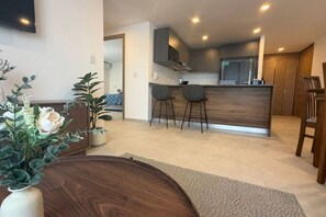 A modern kitchen with a central island, bar stools, and a dining area with a wooden table and chairs. - Departamento Nhaos Minerva (Guadalajara)
