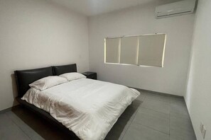 Ein Schlafzimmer mit einem Bett, einem Nachttisch und einer Wand-Klimaanlage.