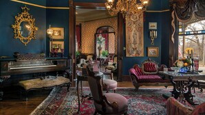A room with a grand piano, ornate furniture, a chandelier, and a large mirror.