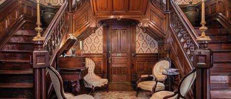 Un magnifique escalier orné de boiseries et de détails en laiton, menant à une porte sur laquelle est inscrit le mot « Patio ».