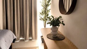 A room with a bed, a small table with a plant, a mirror, and an air conditioning unit. - Departamento NHAOS Minerva (Guadalajara)