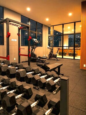 A gym with weightlifting equipment, exercise machines, and large windows. - Departamento NHAOS Minerva (Guadalajara)
