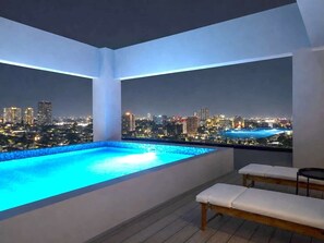 Ein Infinity-Pool auf dem Dach mit Blick auf die nächtliche Skyline der Stadt.