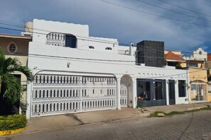 A white building with a gated entrance and a covered area with windows.
